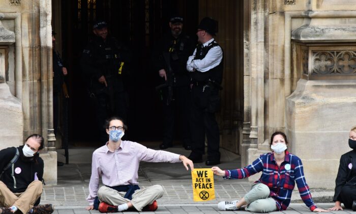 Des militants du groupe Extinction Rebellion sont assis, collés au sol, devant l'une des entrées du Parlement à Londres, le 3 septembre 2020 (Justin Tallis/AFP via Getty Images)