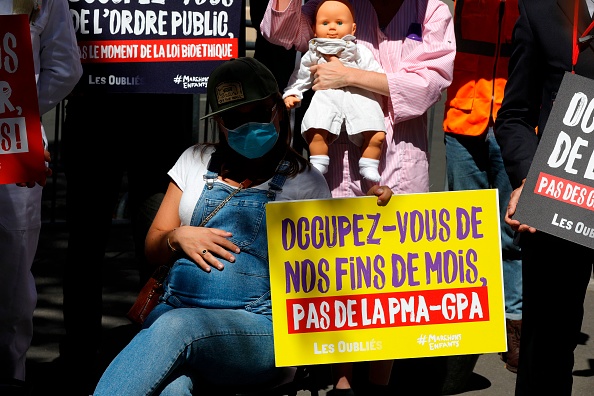 Une militante du collectif de La Manif pour Tous brandit une pancarte hostile à l’extension de la PMA à toutes les femmes, le 27 juillet 2020 devant l’Assemblée nationale à Paris. (Photo : crédit : GEOFFROY VAN DER HASSELT/AFP via Getty Images)