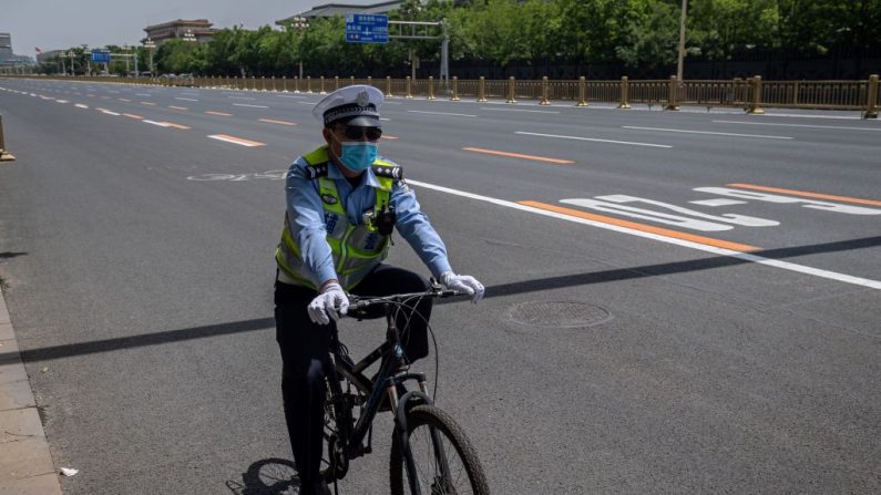 Un policier fait du vélo à Pékin le 18 mai 2020. (Nicolas Asfouri/AFP via Getty Images)