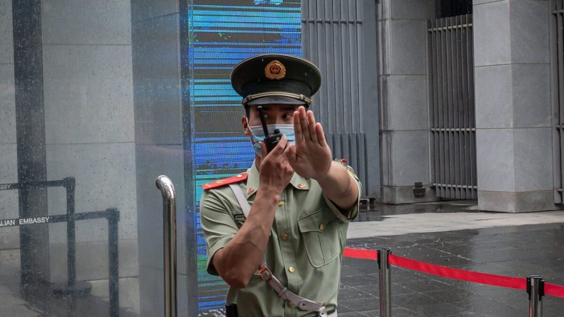 Un policier paramilitaire chinois fait des gestes et parle par radio bidirectionnelle tout en se tenant à la porte d'entrée de l'ambassade d'Australie à Pékin le 9 juillet 2020. (Nicolas Asfouri/AFP via Getty Images)
