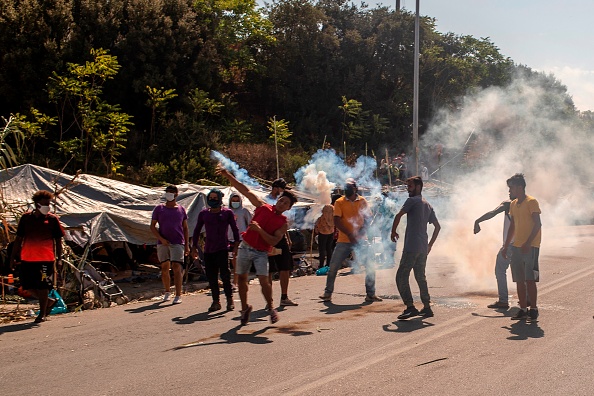 -Les réfugiés et les migrants reçoivent des cartouches de gaz lacrymogènes tirées par la police anti-émeute lors d'affrontements près de la ville de Mytilène sur l'île grecque de Lesbos, le 12 septembre 2020. Photo Angelos Tzortzinis /AFP via Getty Images