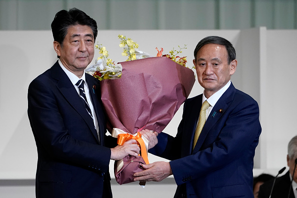 -Le secrétaire en chef du cabinet Yoshihide Suga offre des fleurs au Premier ministre japonais Shinzo Abe après qu’il a été élu nouveau chef du parti au pouvoir le 14 septembre 2020 à Tokyo. Photo par Eugène Hoshiko - Piscine / Getty Images.