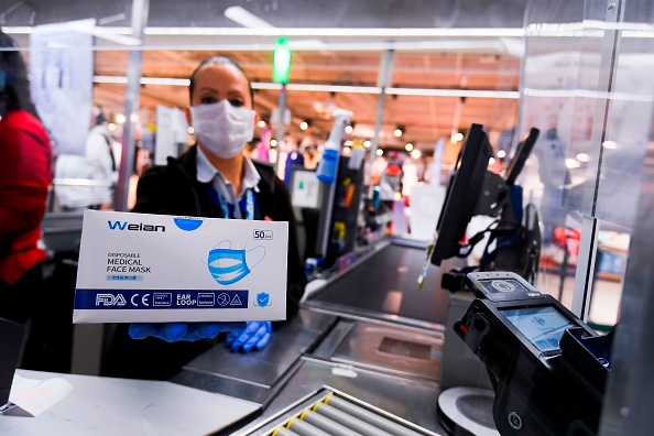 Une caissière montre une boîte de masques chirurgicaux. (LAURIE DIEFFEMBACQ/Belga/AFP via Getty Images)