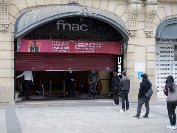 Des clients font la queue à la réouverture du magasin Fnac de l'avenue des Champs-Élysées, à Paris, le 11 mai 2020, au premier jour de l'assouplissement par la France des mesures de confinement mises en place depuis 55 jours pour enrayer la propagation de la pandémie COVID-19, causée par le nouveau coronavirus. (Photo par ERIC PIERMONT / AFP) (Photo par ERIC PIERMONT/AFP via Getty Images)