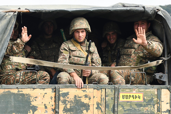 -Des militaires de l'armée de défense du Karabakh saluent à l'arrière d'un camion lors des combats avec l'Azerbaïdjan le 29 septembre 2020. Photo de Narek Aleksanyan / AFP via Getty Images.