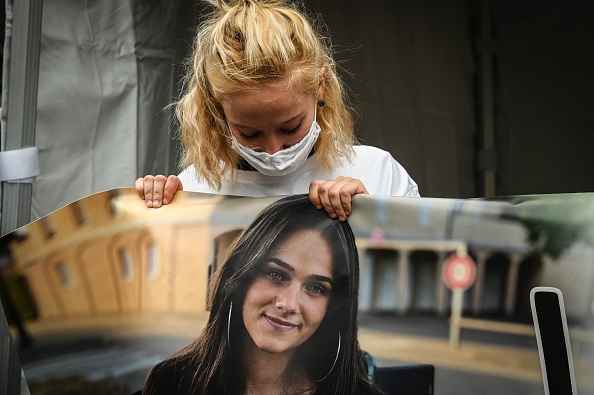 Une des sœurs de Victorine tient une bannière avec la photo de Victorine lors d'une marche blanche à Villefontaine, le 4 octobre 2020. (JEAN-PHILIPPE KSIAZEK/AFP via Getty Images)