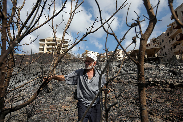 -Un Syrien inspecte une zone brûlée à la suite d'un incendie de forêt qui a ravagé des pans de terres dans la campagne de la ville occidentale de Tartous, le 11 octobre 2020.  Photo par Louai Beshara / AFP via Getty Images.