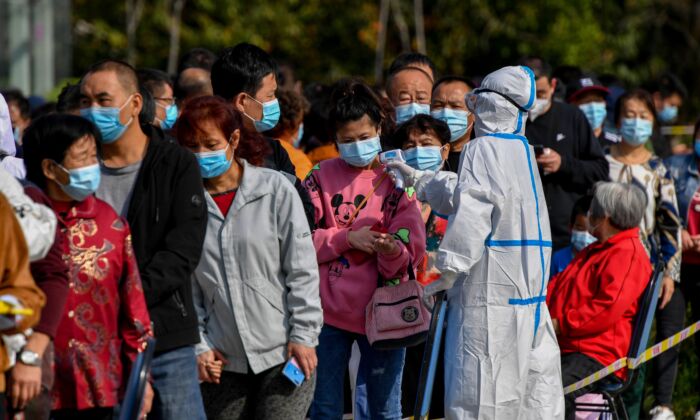 Un agent sanitaire vérifie la température des résidents alors qu'ils font la queue pour être testés pour le Covid-19 à Qingdao, dans la province du Shandong, à l'est de la Chine, le 12 octobre 2020. (STR/AFP via Getty Images)es)