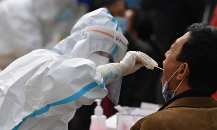 Un soignant prélève un échantillon sur un résident pour le soumettre à un test de dépistage du virus du PCC dans le cadre d'un programme de test de masse suite à une nouvelle épidémie de coronavirus à Qingdao, une ville située dans la province du Shandong, dans l'est de la Chine, le 13 octobre 2020. (STR/AFP via Getty Images)