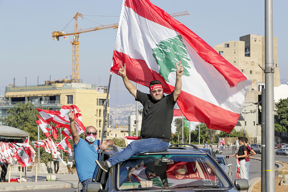 -Des manifestants libanais agitent le drapeau national alors qu'ils se rendent à une manifestation, marquant le premier anniversaire d'un mouvement de protestation, dans le centre-ville de Beyrouth, la capitale, le 17 octobre 2020. Photo par ANWAR AMRO / AFP via Getty Images.