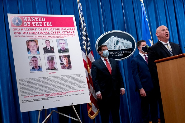 Une affiche montrant six agents du renseignement militaire russe recherchés pour des cyberattaques mondiales, est présente durant la conférence de presse au ministère de la Justice, le 19 octobre 2020 à Washington, DC. (Photo : Andrew Harnik - Pool/Getty Images)