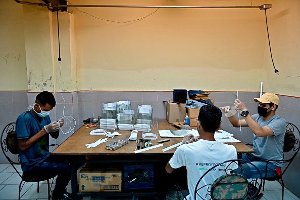-Des bénévoles fabriquent des écrans faciaux dans un ancien atelier de couture à Caracas le 28 octobre 2020. Photo par Federico Parra / AFP via Getty Images.