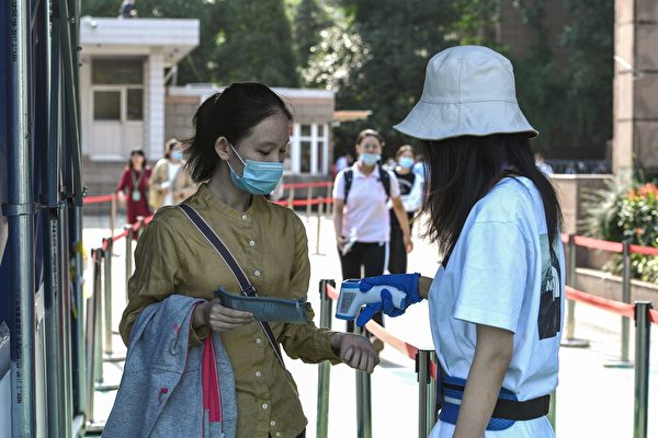 Une étudiante (à gauche) fait vérifier sa température corporelle avant d'entrer dans un établissement scolaire pour passer le concours d'entrée au collège national (NCEE), connu sous le nom de Gaokao, à Nanjing, dans la province orientale du Jiangsu en Chine, le 7 juillet 2020. Près de 11 millions d'étudiants chinois stressés ont passé l'examen annuel d'entrée à l'université après un mois de retard en raison de l'épidémie de coronavirus. Cette année, les inspecteurs ont vérifié qu'il n'y avait ni fraude ni fièvre. (STR/AFP via Getty Images)