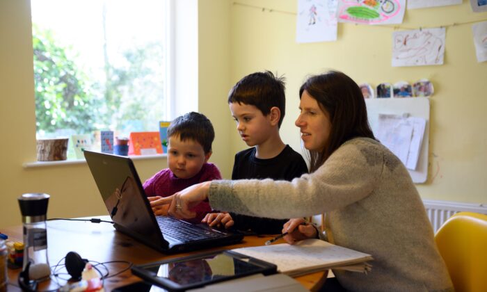 Des enfants sont aidés par leur mère lorsqu'ils se familiarisent avec les ressources pédagogiques en ligne pendant le confinement du virus du PCC à Huddersfield, en Angleterre, le 23 mars 2020. (Oli Scarff/AFP via Getty Images)