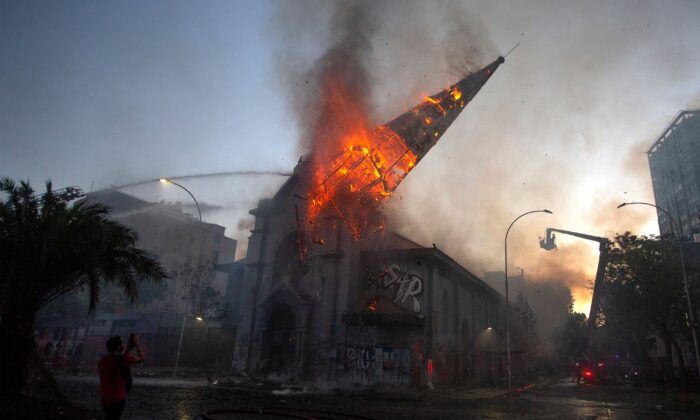 Le clocher de l'église d'Asunción tombe en flammes après avoir été incendié par des émeutiers lors de la commémoration du premier anniversaire du soulèvement social au Chili, à Santiago, le 18 octobre 2020. (Claudio Reyes/AFP via Getty Images)