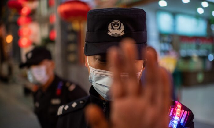 Un policier portant un masque facial contre le Covid-19 tente d'empêcher un photojournaliste de prendre des photos dans une rue à l'extérieur d'un complexe commercial à Pékin le 13 octobre 2020. (Nicolas Asfouri/AFP via Getty Images)