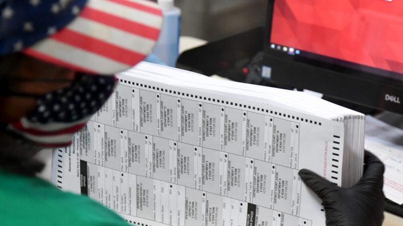 Un employé du comté de Clark scanne les bulletins de vote envoyés par la poste au département électoral du comté de Clark à North Las Vegas, Nevada, le 7 novembre 2020. (Ethan Miller/Getty Images)