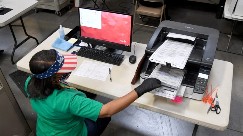 Un employé du comté de Clark scanne les bulletins de vote envoyés par la poste au département électoral du comté de Clark à North Las Vegas, Nev. le 7 novembre 2020. (Ethan Miller/Getty Images)