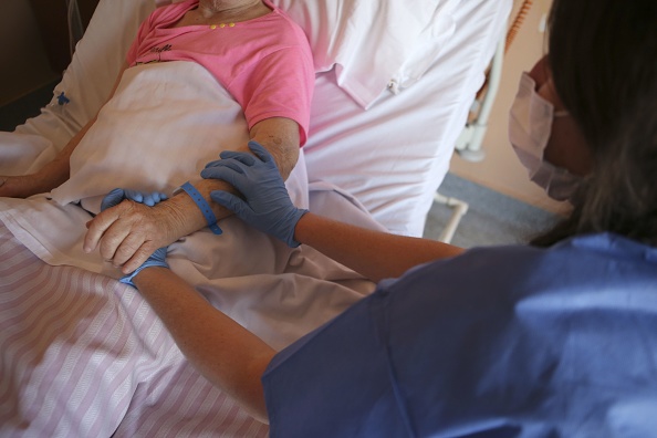 Image d'illustration : une infirmière tient la main d'une dame à l'unité de soins palliatifs dans un hôpital d'Ajaccio. (PASCAL POCHARD-CASABIANCA/AFP via Getty Images)