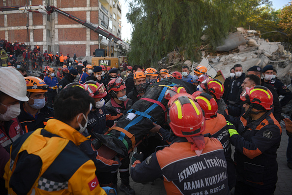 -Les sauveteurs portent un corps pendant l'opération de recherche en cours sur le site d'un bâtiment effondré alors qu'ils recherchent des survivants et des victimes dans la ville d'Izmir le 2 novembre 2020. Photo par Ozan  Kose / AFP via Getty Images.