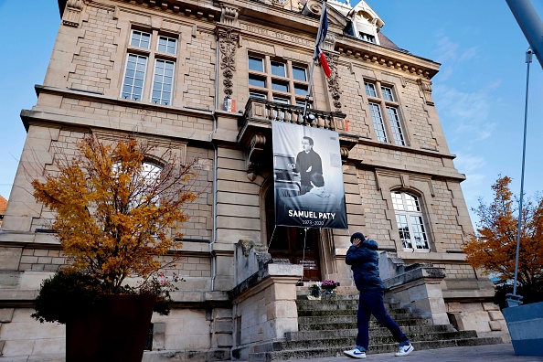 Un piéton passe devant une affiche représentant le professeur de français Samuel Paty placée sur la façade de l'hôtel de ville de Conflans-Sainte-Honorine, à 30 km au nord-ouest de Paris, le 3 novembre 2020, suite à la décapitation du professeur le 16 octobre.  (THOMAS COEX/AFP via Getty Images)