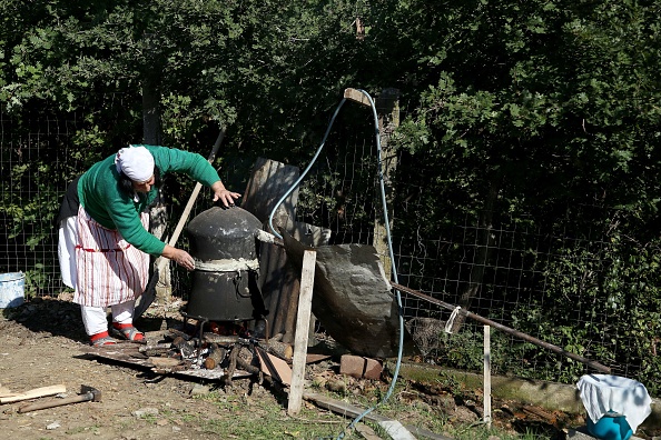 -Au fond de son jardin, la mère de cinq enfants Vitore Lufi fait du raki, une eau-de-vie de fruits célébrée par les Albanais. Photo par Gent Shkullaku / AFP via Getty Images.