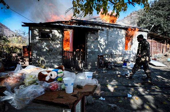 -Un homme passe devant une maison qui brûle dans le village de Charektar, à l'extérieur de la ville de Kalbajar, le 14 novembre 2020. Photo par Alexander Nemenov / AFP via Getty Images.