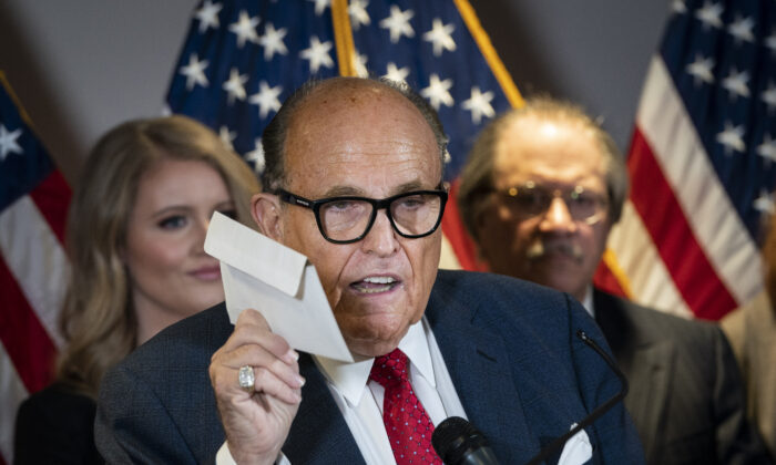 Rudy Giuliani brandit un bulletin de vote par correspondance alors qu'il parle à la presse de diverses poursuites liées à l'élection de 2020, au siège du Comité national républicain à Washington le 19 novembre 2020. (Drew Angerer/Getty Images)