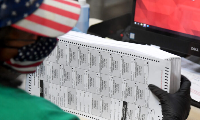Un employé électoral du comté de Clark scrute les bulletins de vote par correspondance au département électoral du comté de Clark à North Las Vegas, le 7 novembre 2020. (Ethan Miller/Getty Images)