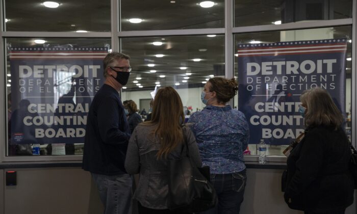 Les observateurs électoraux (challengers) regardent par la fenêtre après avoir appris que la capacité d'accueil des observateurs a été atteinte pour le moment au Central Counting Board du TCF Center à Detroit, Michigan, le 4 novembre 2020. (Elaine Cromie/Getty Images)