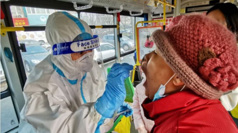 Un employé de la santé prélève un échantillon sur un habitant pour détecter le COVID-19 à Dalian, en Chine, le 23 décembre 2020. (STR/AFP via Getty Images)