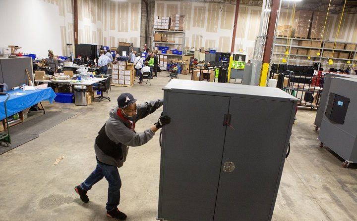 Un employé du comté de Fulton déplace des transporteurs de machines à voter qui seront stockés au centre de préparation des élections du comté de Fulton à Atlanta, en Géorgie, le 4 novembre 2020. (Jessica McGowan/Getty Images)