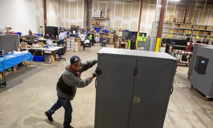 Un employé du comté de Fulton déplace des transporteurs de machines à voter qui seront stockés au centre de préparation des élections du comté de Fulton à Atlanta, Ga. le 4 novembre 2020. (Jessica McGowan/Getty Images)