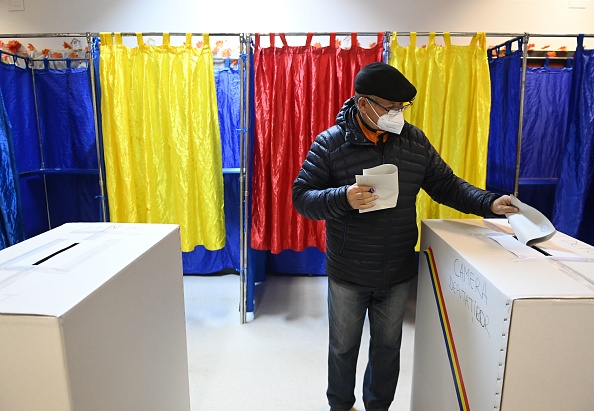 -Un homme dépose son bulletin dans un bureau de vote à Bucarest lors des élections législatives du 6 décembre 2020. Photo par Daniel Mihailescu / AFP via Getty Images.