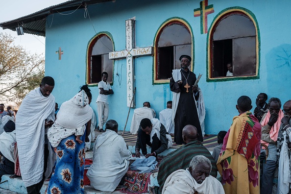 -Un prêtre orthodoxe éthiopien se tient devant les fidèles lors d'une messe dominicale à laquelle assistaient des croyants et des réfugiés locaux qui ont fui le conflit du Tigray, le 6 décembre 2020. Photo par Yasuyoshi Chiba / AFP via Getty Images.