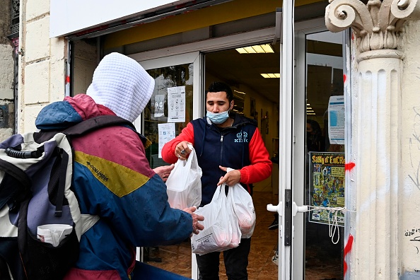 Un bénévole donne des paquets de nourriture à un homme au Noga, un restaurant social à Marseille, le 10 décembre 2020. Photo par Nicolas Tucat / AFP via Getty Images.