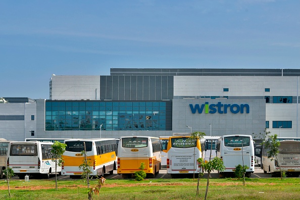 -Des bus se trouvent devant l'entrée de Wistron, une usine d'iPhone dirigée par des Taiwanais, à Narsapura, à environ 60 km de Bangalore le 13 décembre 2020. Photo :  Manjunath Kiran / AFP via Getty Images).