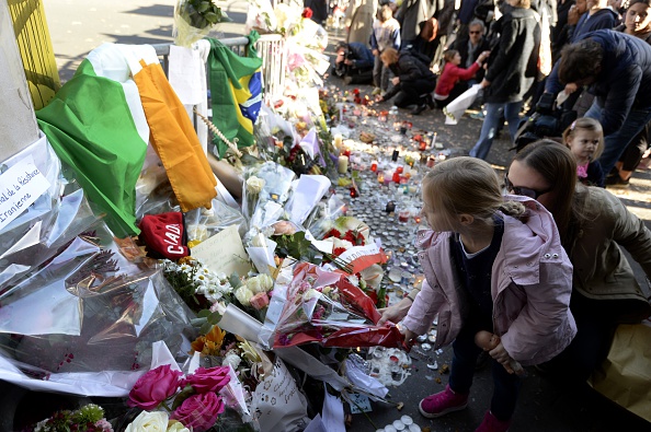 -Un enfant place un bouquet de fleurs le long d'un cordon de police installé près de la salle de concert du Bataclan le 15 novembre 2015 à Paris. À la suite de ces attaques de nombreux enfants sont devenus pupilles de la Nation. Crédit photo doit lire MIGUEL MEDINA / AFP via Getty Images.