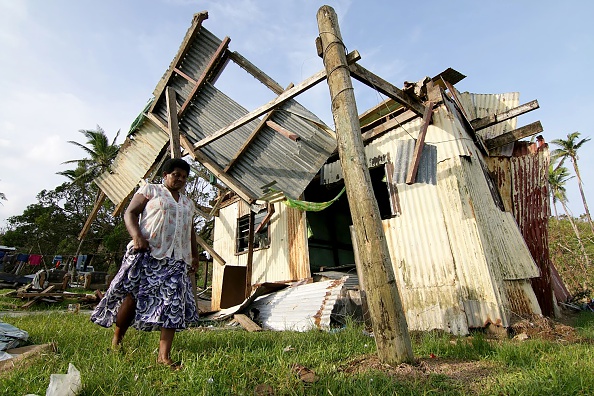 -Illustration- Une femme du village de Namena marche devant sa maison endommagée après que le cyclone a balayé la zone. Photo Steven Saphore / AFP via Getty Images.