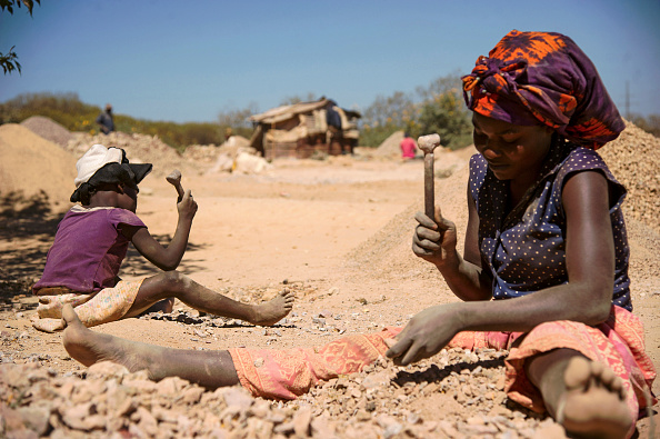 Un enfant et une femme cassent des roches extraites d'une mine de cobalt dans une carrière de cuivre et une fosse de cobalt à Lubumbashi le 23 mai 2016.    (JUNIOR KANNAH/AFP via Getty Images)