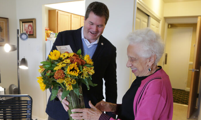 Le PDG de Random Acts of Flowers, Larsen Jay, livre le 100 000e bouquet de l'association à Joan Taylor, une personne âgée à Chicago. (Jean Marc Giboux/AP Images pour FTD et ProFlowers).