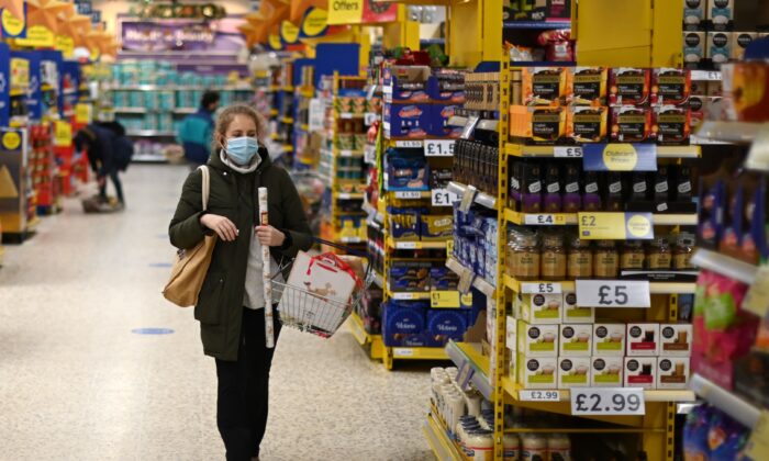Une femme portant un masque de protection magasine dans les allées d'un supermarché Tesco, à Londres, Angleterre, le 14 décembre 2020. (Daniel Leal-Olivas/AFP via Getty Images)