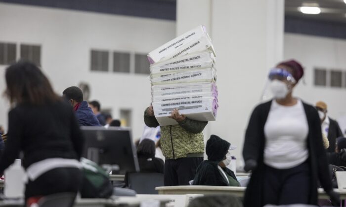 Un employé du département des élections de Détroit transporte des boîtes vides utilisées pour organiser les votes par correspondance après la fin du dépouillement des votes par correspondance au Central Counting Board du centre TCF de Détroit, Michigan, le 4 novembre 2020. (Elaine Cromie/Getty Images)