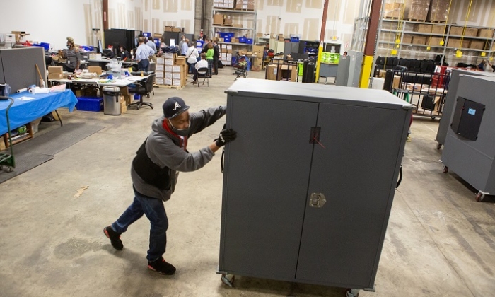 Un employé du comté de Fulton déplace des transporteurs de machines à voter qui seront entreposés au centre de préparation des élections du comté de Fulton à Atlanta, en Georgie, le 4 novembre 2020. (Jessica McGowan/Getty Images)