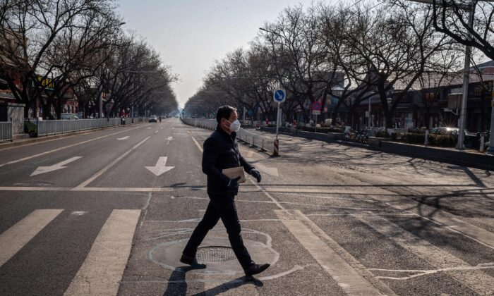 Un homme portant un masque de protection et des gants marche dans une rue presque vide de Pékin le 23 février 2020. (Nicolas Asfouri/AFP via Getty Images)