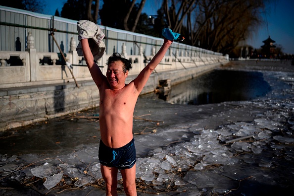 Un homme s'étire après avoir nagé dans le lac glacé d’Houhai à Pékin le 7 janvier 2021. Photo par Noël Celis / AFP via Getty Images.