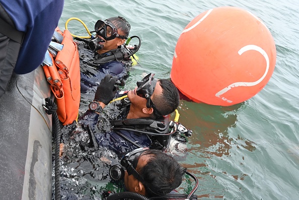 -Des plongeurs de la marine utilisent un dispositif de flottaison pour soulever des débris lourds lors d'opérations de récupération près de l'île de Lancang le 10 janvier 2021.  Photo par Adek Berry / AFP via Getty Images.