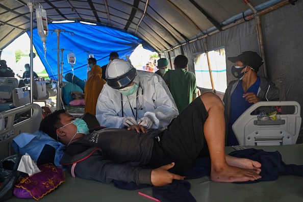 -Un homme blessé dans le tremblement de terre indonésien reçoit des soins dans un service de fortune à l'extérieur d'un hôpital à Mamuju le 17 janvier 2021. Photo Adek Berry / AFP via Getty Images.