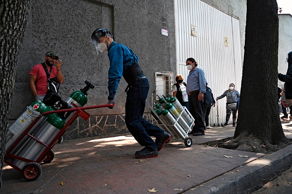 -Un employé de la société Infra Medica transporte des réservoirs d'oxygène à Mexico, le 22 janvier 2021.Photo de Rodrigo Arangua / AFP via Getty Images.