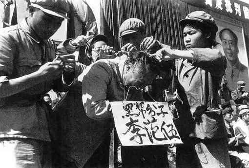 Des jeunes communistes accrochent une pancarte au cou d'un homme lors de la Révolution culturelle en Chine. La pancarte indique son nom et l'accuse d'être un membre de la « classe noire ». (Domaine public)
